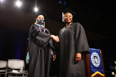 student walks across 2021 commencement stage