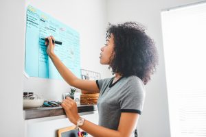 Attack Your Day! Before it Attacks You - a picture of a young woman tracking her progress on a poster board.