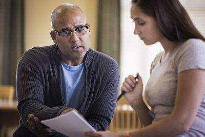 Building a Supportive Network - a picture of a professor reviewing a students' work.