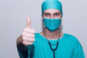 Nurse as a Champion- a picture of a mature, male nurse giving a thumbs-up under a COVID facemask.