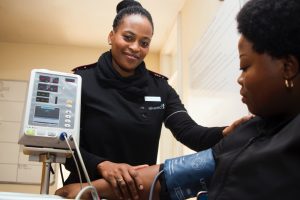 Nurse as a Champion- a picture of a mature, young female nurse checking the pulse of a female patient.