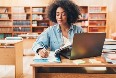 Graduate Support in the Virtual Library - a picture of a young woman studying and taking notes.