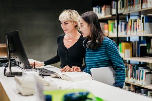 Graduate Support in the Virtual Library - a picture of a young women studying together in the library at a computer.