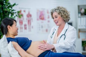 Nurse Midwife Certification: Everything You Need to Know - a picture of a cnm examining a pregnant patient.