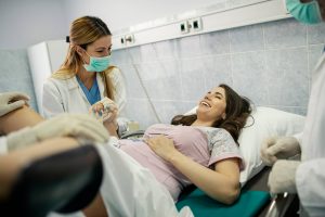 Nurse Midwife Certification: Everything You Need to Know - a picture of a nurse midwife holding hands with a patient during birth. 