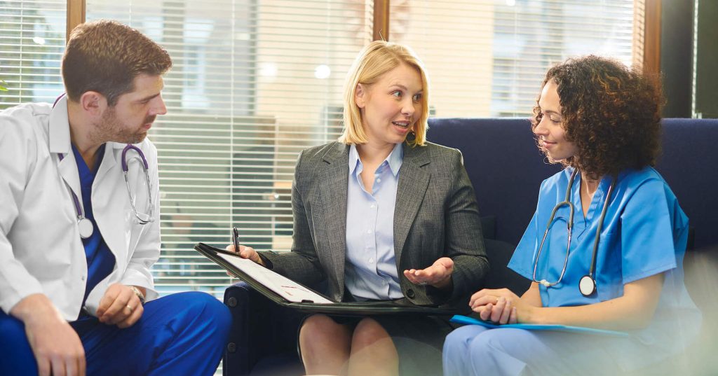 Administrative healthcare - a picture of a healthcare administrator speaking with faculty doctors.