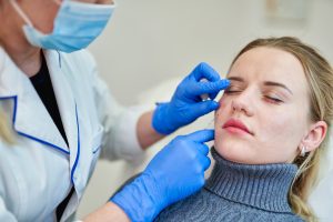 Aesthetics Nurse: A Comprehensive Guide - a picture of a nurse beginning an eye treatment on a female patient.