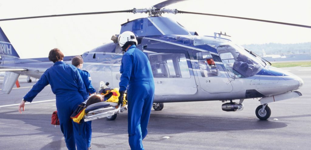 Flight nurse - a picture of nurses carrying a patient on a stretcher towards a waiting helicopter.