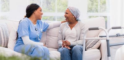 Hospice Nurse: An informative career guide - a picture of a hospice nurse laughing with a sick patient in her home.