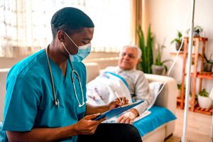 In-Home Care Nurse Career Guide 2022 - a picture of a nurse documenting in front of a patient.