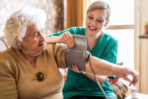 In-Home Care Nurse Career Guide 2022 - a picture of a nurse putting a pressure cuff on an elderly patient.
