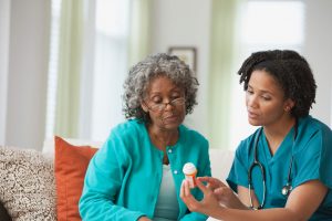 In-Home Care Nurse Career Guide 2022 - a picture of a nurse reviewing medicine with a patient.
