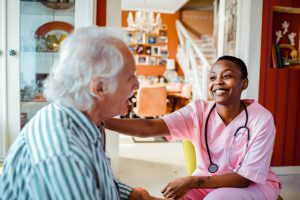 In-Home Care Nurse Career Guide 2022 - a picture of a nurse smiling with a elderly patient.