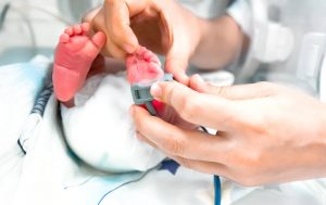 NICU Nurse: How to Become a Neonatal Nurse - a picture of a NICU nurse putting an oxygenator on a premature newborn baby's foot.