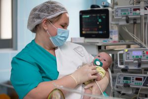 NICU Nurse: How to Become a Neonatal Nurse - a picture of a NICU nurse holding a newborn. 