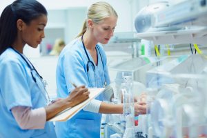 NICU Nurse: How to Become a Neonatal Nurse - a picture of a NICU nurses checking a newborn in an incubator.