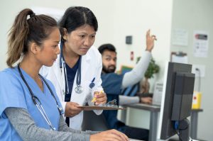 Nurse Teacher (aka Nurse Educator)_ The Complete Career Guide - a picture of a nurse educator checking a student's work.