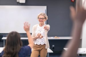 Nurse Teacher (aka Nurse Educator): The Complete Career Guide - a picture of a nurse educator smiling and pointing at a student.