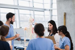 Nurse Teacher (aka Nurse Educator)_ The Complete Career Guide - a picture of a nurse educator using a skeleton to teach students about anatomy.