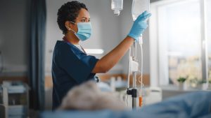 PACU (post-anesthesia care unit) Nurses Job Description and 2023 Outlook - a picture of a PACU nurse handling an IV drip.