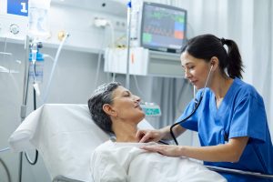 PACU (post-anesthesia care unit) Nurses Job Description and 2023 Outlook - a picture of a PACU nurse listening to the heart of her patient. 